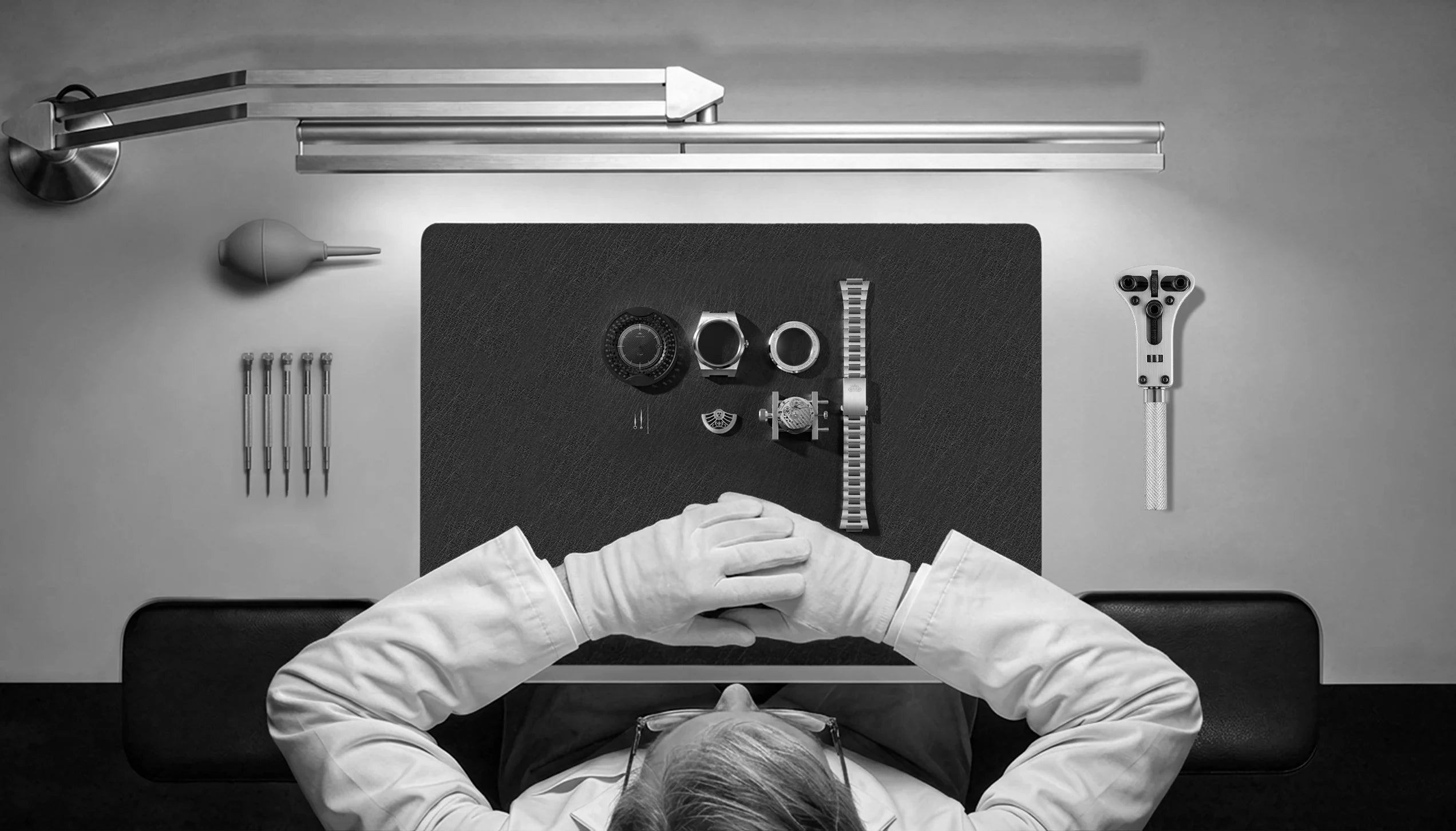 Composants de la Belvans Daylee et outils d'horloger sur l'établi, photo en noir et blanc.