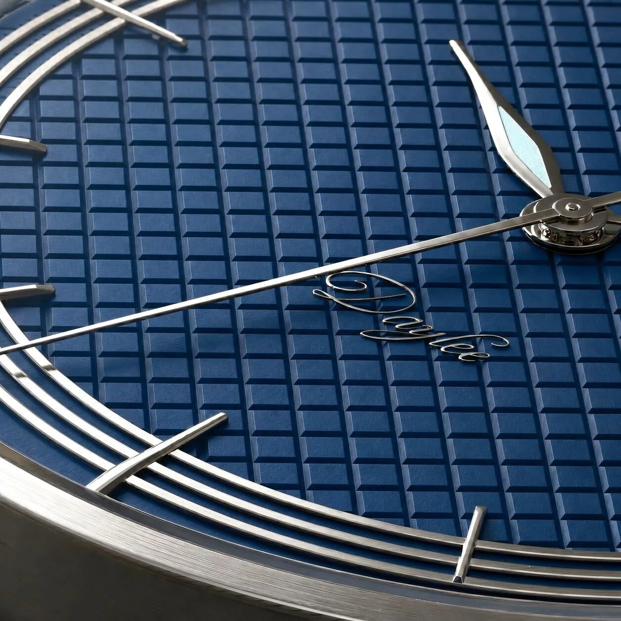 Macro du cadran bleu guilloché de la montre Belvans Daylee, aiguille dauphine et signature.