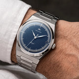 Montre automatique Belvans Daylee cadran bleu portée au poignet avec bracelet acier intégré.