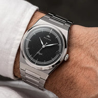 Montre automatique Belvans Daylee cadran noir portée au poignet avec bracelet acier intégré.