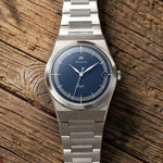 Montre Belvans Daylee cadran bleu et bracelet acier posée sur bois.