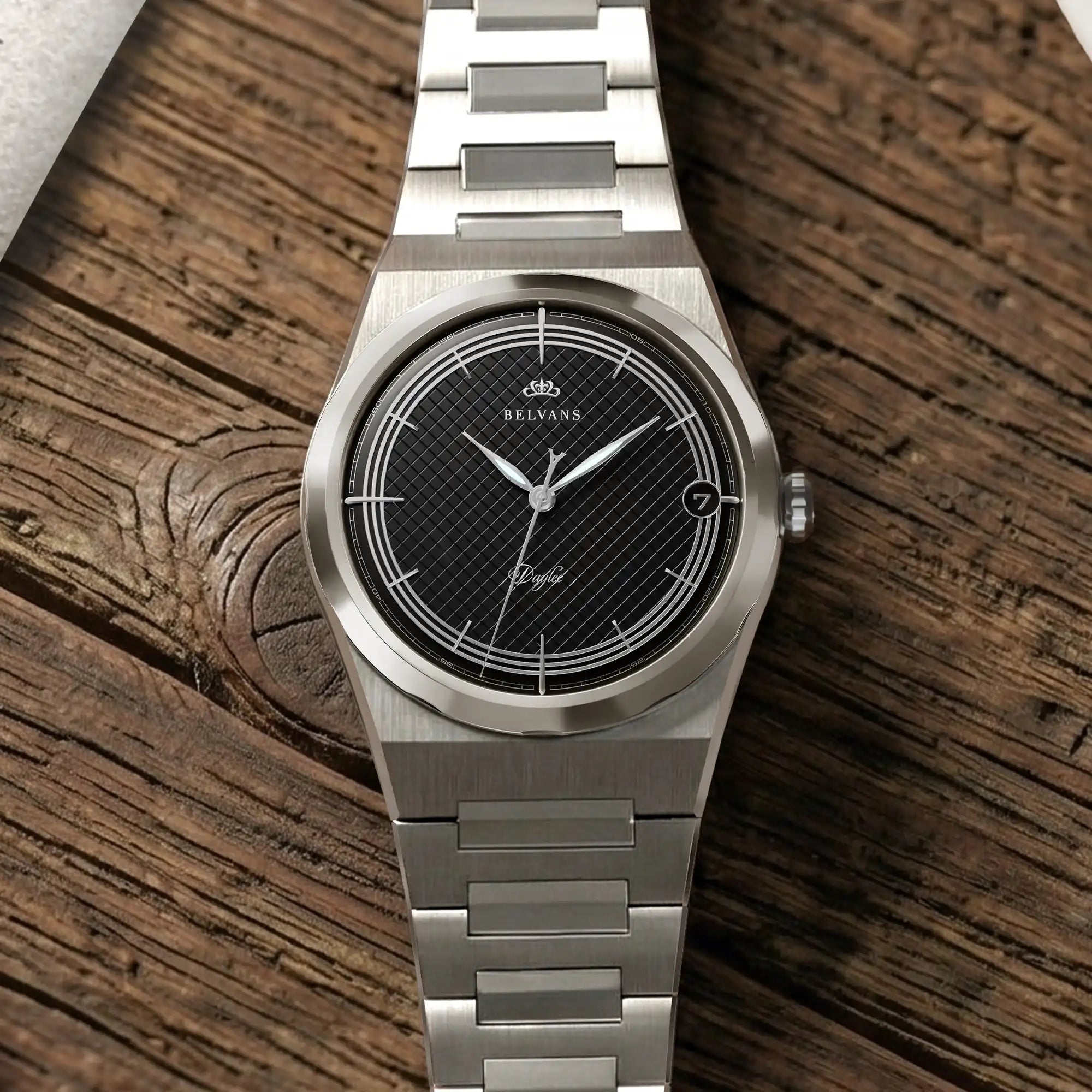 Montre Belvans Daylee cadran noir et bracelet acier posée sur bois.